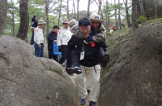 이번 금강산 통일행사에 참가한 엘지전자노동조합 소속 자원봉사자가 지체장애인을 업고 금강산을 오르고 있다 